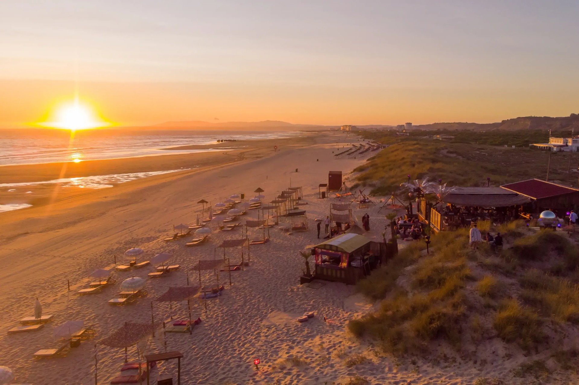 Praia Irmão beach club on the sand at Costa da Caparica at sunset
